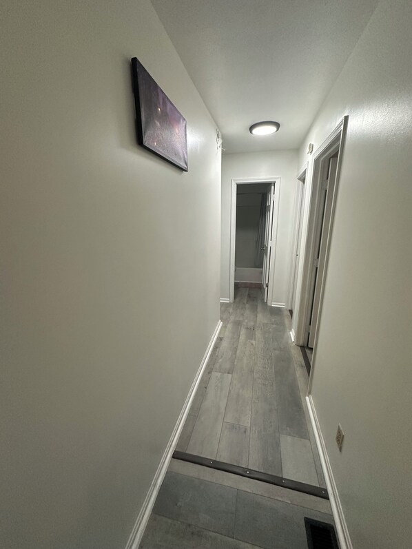 A hallway with a light-colored floor, white walls, and a ceiling light. - Live. Love. Sleep!. (Berea)