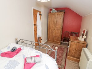 A bedroom with a bed, a wooden wardrobe, a chair, a desk, and a radiator. - Bodorwel Cottage (Penrhyndeudraeth)