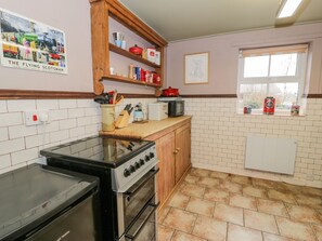 A kitchen with a stove, oven, and a window with a view. - Bodorwel Cottage (Penrhyndeudraeth)