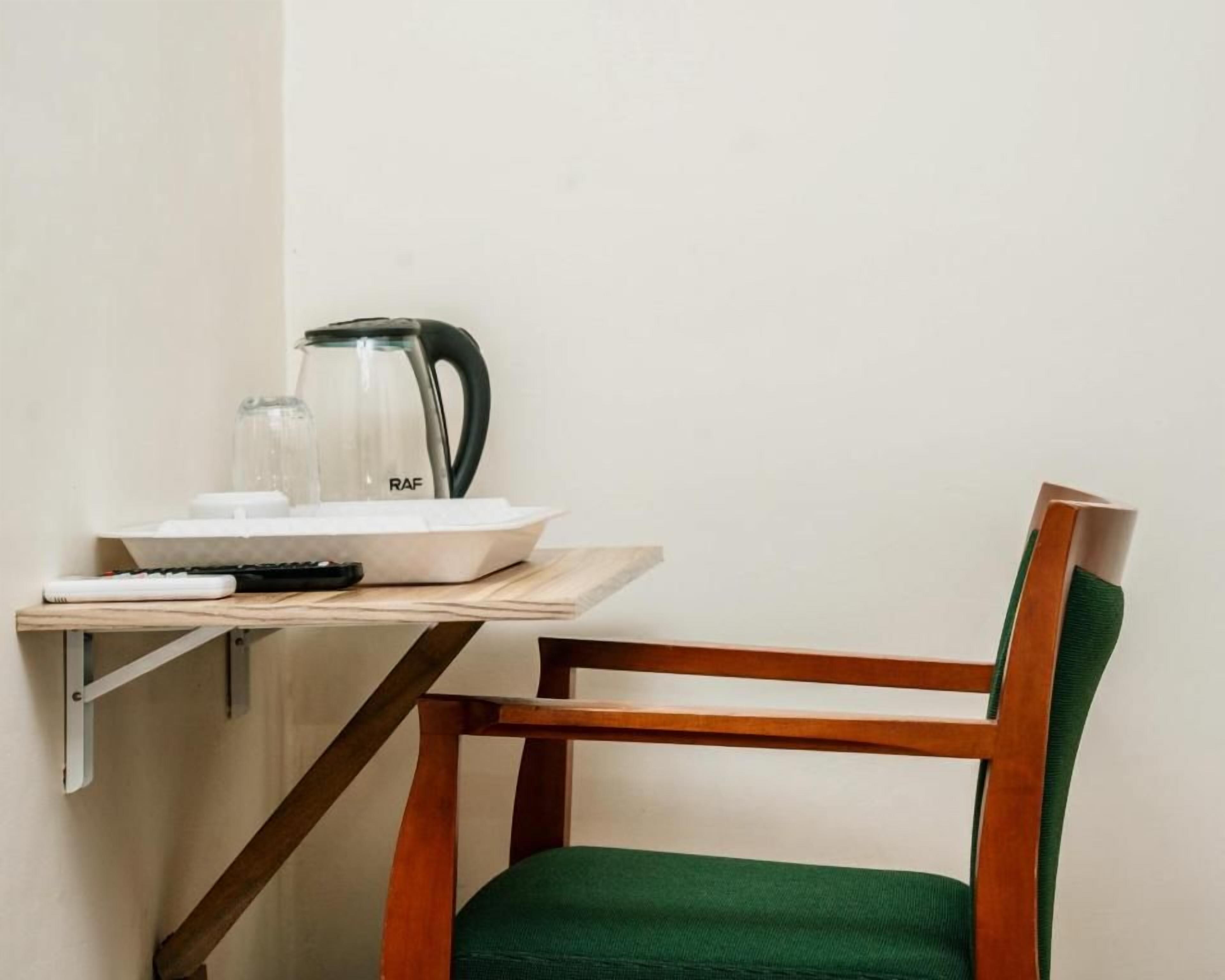 Una pequeña kitchenette con una cafetera, un hervidor y un bol sobre una mesa de madera.