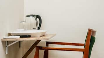 Una pequeña kitchenette con una cafetera, un hervidor y un bol sobre una mesa de madera.