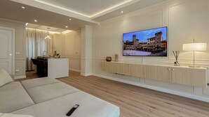 A modern living room with a sofa, a TV mounted on the wall, a dining area, and a lamp. - The Golden Key
Your Charme Appartment in Tuscany (Arezzo)