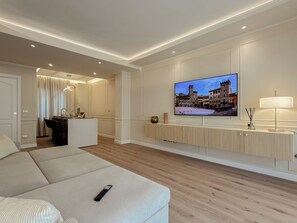 Un salon moderne avec un canapé, un téléviseur fixé au mur, un coin repas et une lampe.