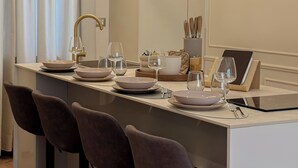 A modern dining area with a long table, three bar stools, a pendant light, and a tablet on the table. - The Golden Key
Your Charme Appartment in Tuscany (Arezzo)