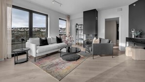 A modern living room with a white sofa, grey armchair, and a coffee table. - TotalApartments Gjøa Premium (Tromsø)