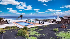 A pool area with lounge chairs, a view of the ocean, and a rocky landscape. - Casa Buenavista • Pool • Ocean views • Beach 2 min • LVH (Famara)