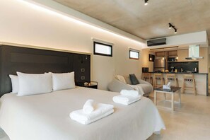 A modern hotel room with a large bed, a small kitchenette, and a seating area. - Portal Arévalo in Palermo by Magno | 42 (Buenos Aires)