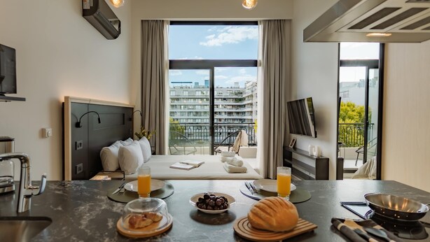 A modern hotel room with a large window, a dining area with breakfast, a bed, and a TV. - Portal Arevalo in Palermo by Magno | 81 (Buenos Aires)