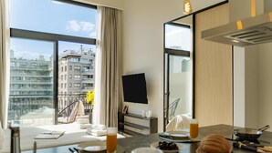 A modern hotel room with a balcony, a dining area with breakfast items, and a flat-screen TV. - Portal Arevalo in Palermo by Magno | 81 (Buenos Aires)