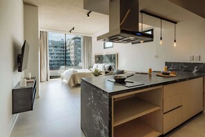 A modern kitchen with a marble countertop, built-in oven, and hanging light fixtures. - Portal Arévalo in Palermo by Magno | 72 (Buenos Aires)