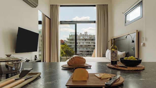 Una cocina con hogaza de pan, una botella de vino y un cuenco de uvas sobre la encimera.