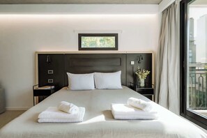 A hotel room with a large bed, two bedside tables, a window with curtains, and a small picture above the bed. - Portal Arévalo in Palermo by Magno | 51 (Buenos Aires)