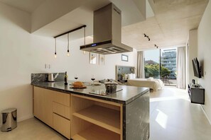 A modern kitchen with a central island, a built-in oven, and pendant lighting. - Portal Arévalo in Palermo by Magno | 71 (Buenos Aires)