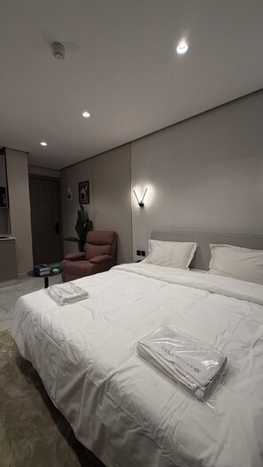 Ein modernes Hotelzimmer mit einem großen Bett, einem Sessel, einem Schreibtisch und einer Pflanze.