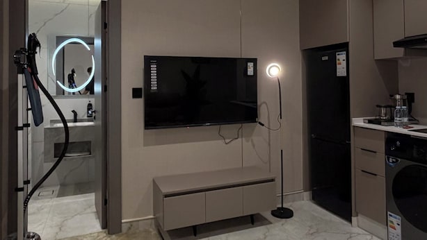 A modern hotel room with a flat-screen TV, air conditioning, a bench, and a small kitchen area. - 007s Tara-jre Jabal Al Lweibdeh With Stunning View (Amman)