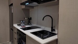 A compact kitchen with a microwave, sink, and built-in oven. - 007s Tara-jre Jabal Al Lweibdeh With Stunning View (Amman)