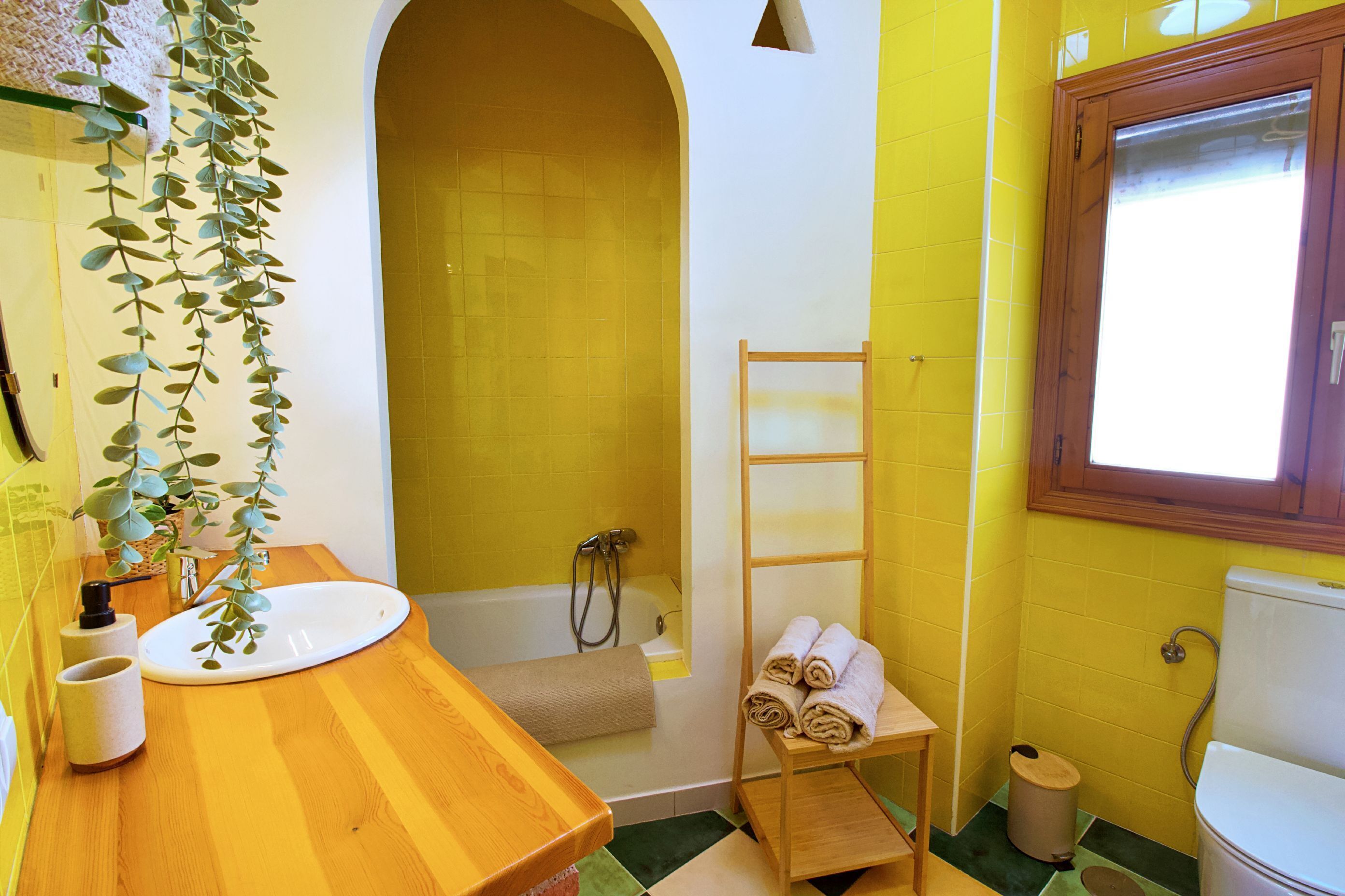 A bathroom with a wooden vanity, a bathtub, a toilet, and a towel rack.