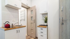 Cocina compacta con encimera de madera, hervidor, pileta y planta en maceta.