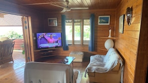 A wooden interior with a television, sofa, and a ceiling fan.