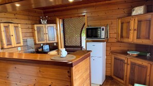 A wooden cabin kitchen with a central island, wooden cabinets, a microwave, and a refrigerator.