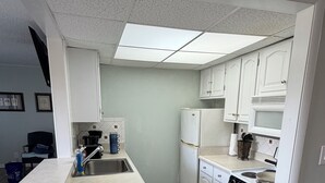 A modern kitchen with a central island, white cabinetry, a built-in oven, and a stainless steel sink. - Cozy 1-bedroom condo in lovely Diamondhead with AC (Diamondhead)