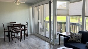 A spacious room with a dining table, chairs, a sofa, a coffee table, and a ceiling fan. - Cozy 1-bedroom condo in lovely Diamondhead with AC (Diamondhead)