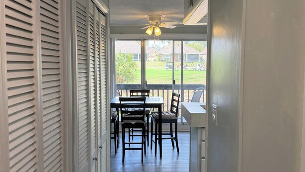 A corridor leading to a dining area with a view of a green lawn and parked cars. - Cozy 1-bedroom condo in lovely Diamondhead with AC (Diamondhead)