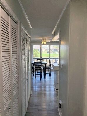 A corridor leading to a dining area with a view of a green lawn and parked cars. - Cozy 1-bedroom condo in lovely Diamondhead with AC (Diamondhead)