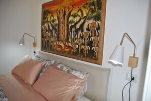 A bedroom with a bed, two bedside lamps, and a large wildlife painting on the wall. - Saha Retreat with Private Patio (Itri)