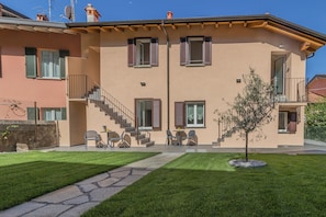 A two-story building with a balcony, a staircase, and a small tree in the front yard. - Cà Magnolia Appartamento 1 by Varenna Holidays (Lierna)
