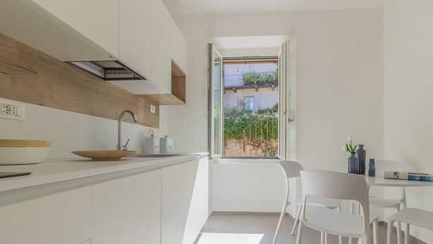 Eine moderne Küche mit weißen Schränken, einer Holzauskleidung und einem Fenster mit Blick auf einen Garten.