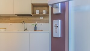 A modern kitchen with white cabinets, a wooden countertop, a built-in shelf with containers, a faucet, and a power outlet. - Cà Magnolia Appartamento 2 by Varenna Holidays (Lierna)