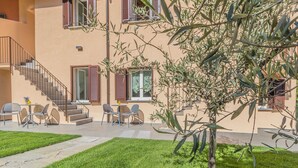 A building with a staircase, outdoor seating, and a well-maintained lawn. - Cà Magnolia Appartamento 4 by Varenna Holidays (Lierna)