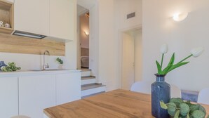 A modern kitchen with white cabinets, a wooden countertop, and a vase with green foliage. - Cà Magnolia Appartamento 4 by Varenna Holidays (Lierna)