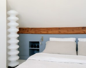 A bedroom with a wooden headboard, a white bed, and a wall-mounted shelf with bottles. - Apartment of 78 m² in Neuilly-sur-Seine (Neuilly-sur-Seine)