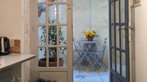Eine schmale Küche mit einer Tür zu einem Patio mit Tisch, Stühlen und Topfpflanzen.