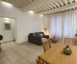 A living room with a sofa, a wooden dining table, and a vase. - Bright Nîmes Center Flat with Terrace (Nîmes)