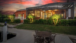 Una casa moderna con un porche cubierto, una piscina y un jardín bien cuidado.