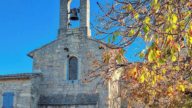 Eine steinerne Kirche mit Glockenturm, Rundbogenöffnung und Blumentöpfen im Vordergrund.