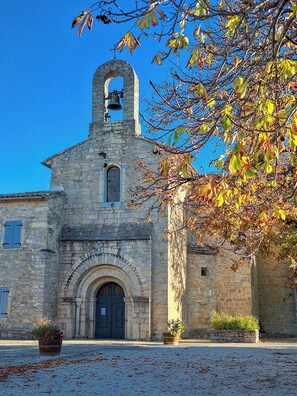 A stone church with a bell tower, arched entrance, and potted plants in the foreground. - Charming village house - 3 bedrooms (Claret)
