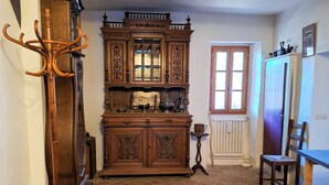 Ein traditionell eingerichteter Raum mit Holzschrank, Kleiderhaken, Heizkörper und Fenster.