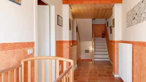 A hallway with a wooden railing, a white door, a staircase, and a radiator.