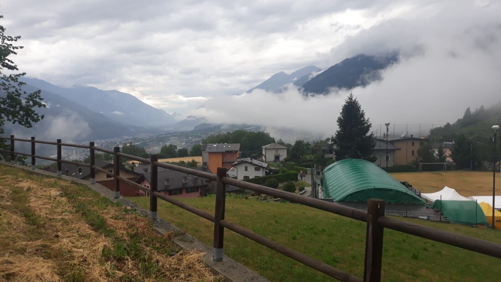 Eine gebirgige Landschaft mit Blick auf Häuser und einem grünen Zelt.