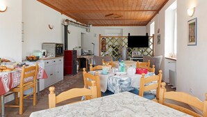A dining area with a marble table, wooden chairs, and a kitchen in the background.