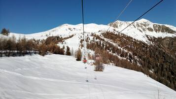Un télésiège se déplace le long d’une pente enneigée, avec une montagne en arrière-plan.