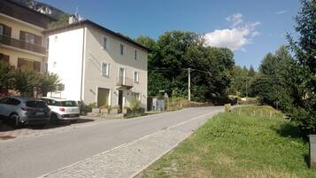 Eine Wohnstraße mit einem zweistöckigen Gebäude, parkenden Autos und einem Kopfsteinpflasterweg.
