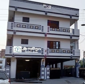 A multi-story building with a garage entrance, balconies, and a logo indicating a real estate listing. - Thamira Residency (Palayankottai)