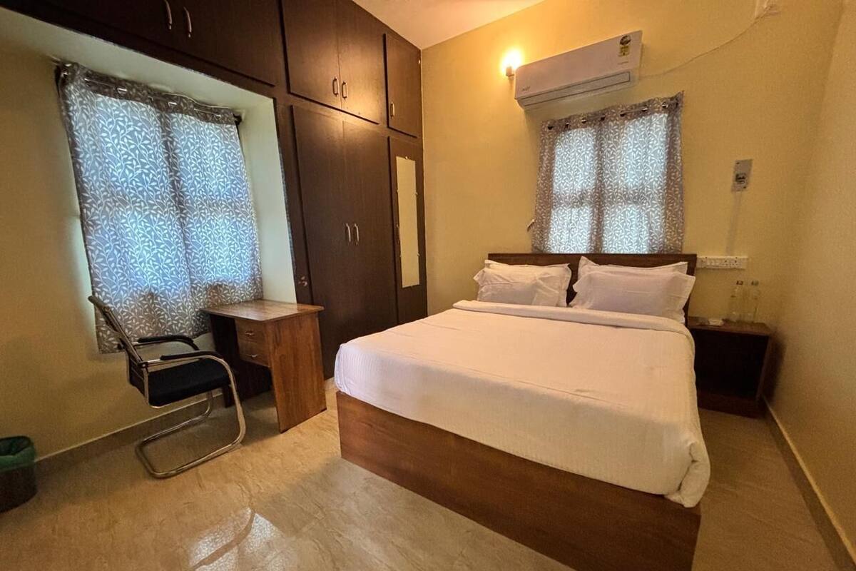 Une chambre à coucher comprenant un lit, un bureau, une chaise, une armoire et un appareil de climatisation.