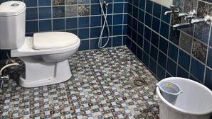 A bathroom with a toilet, a shower, and a trash bin. - Thamira Residency (Palayankottai)