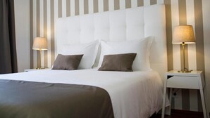 Una habitación de hotel con una cama grande, dos lámparas de noche y una pared a rayas.